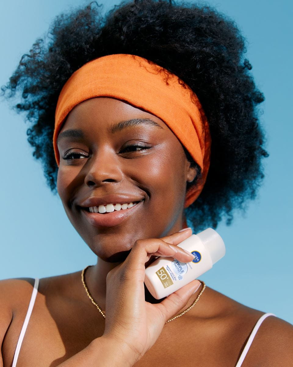 cheveux afro femme tenant une crème Nivea SPF 50