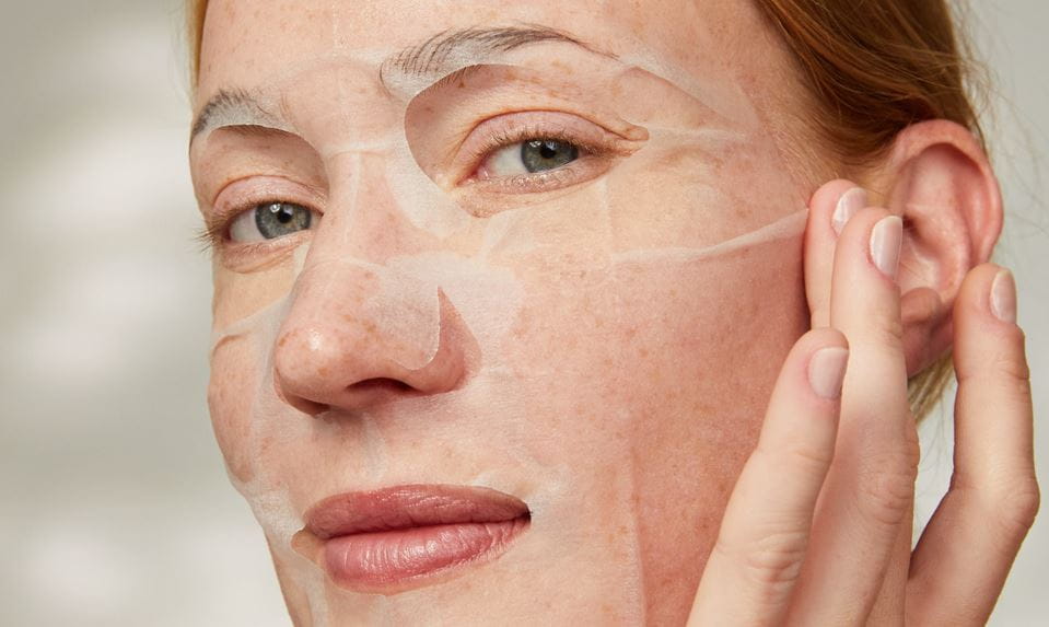 kvinna som applicerar en återfuktande ansiktsmask