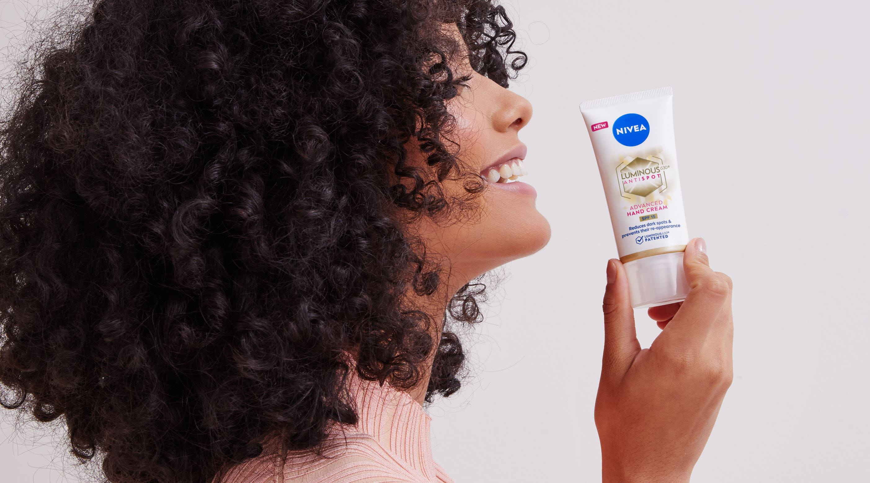 girl with curly hair holding a Nivea hand cream