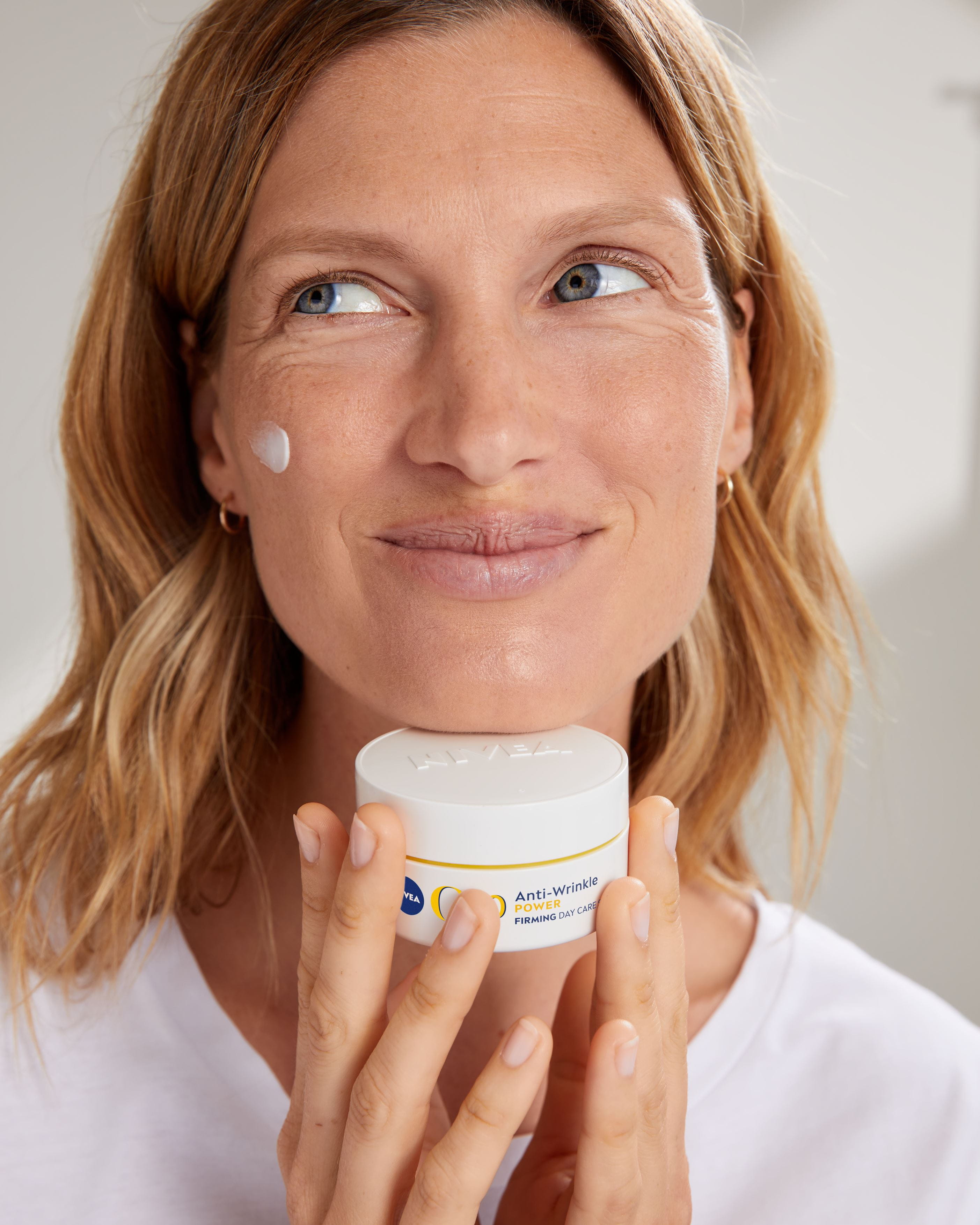 mujer sosteniendo una crema facial Nivea