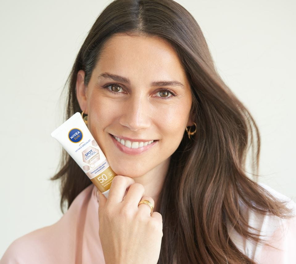 kvinna som håller i en Nivea Sun Spot Control Face Cream