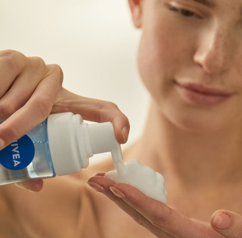 млада жена използва почистващ препарат за лице Nivea
