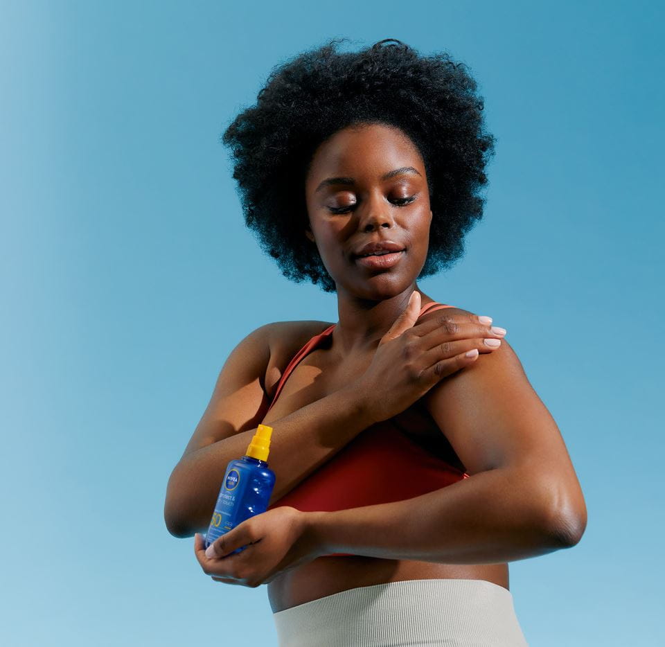 Afrohårkvinna som applicerar Nivea SPF-kräm