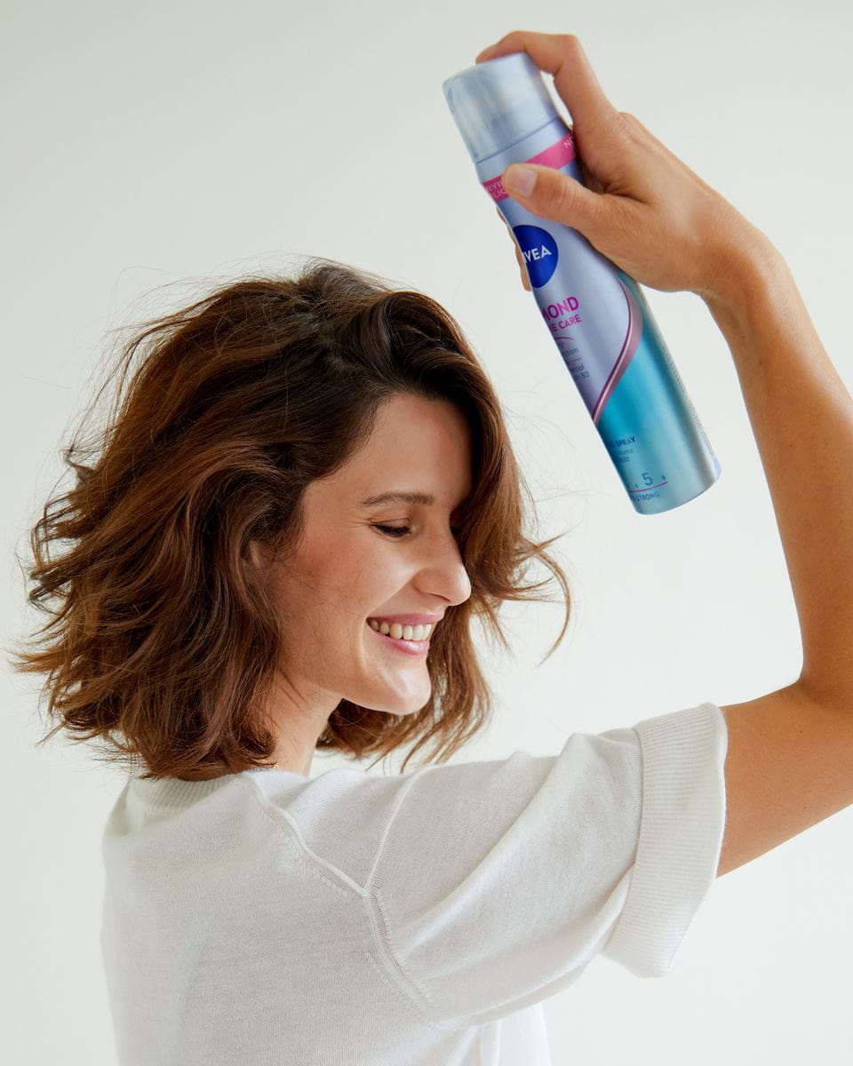 eine Frau, die ihr Haar mit Haarspray besprüht