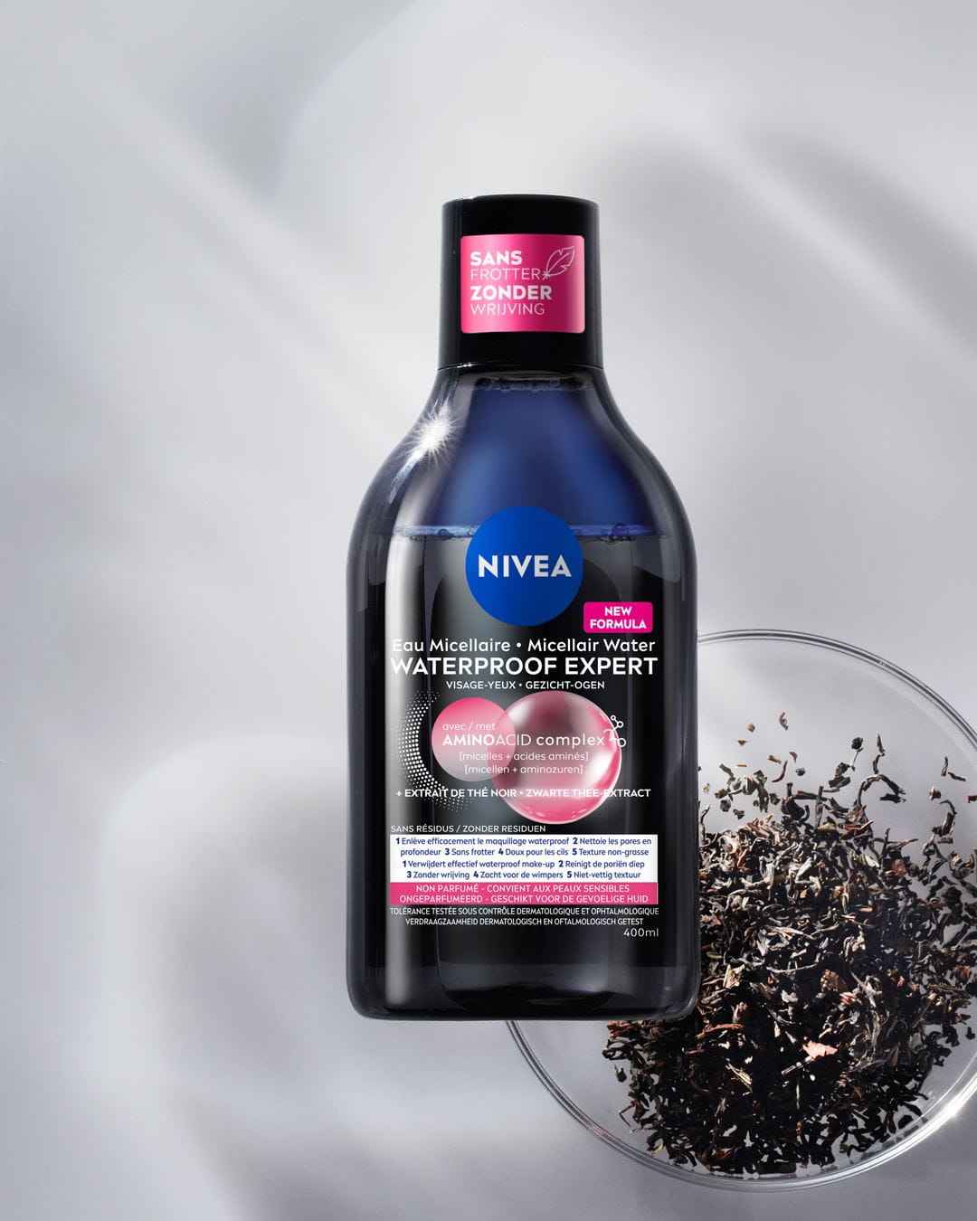Een flesje NIVEA Micellair Water voor alle huidtypes ligt op een zwarte bubbelachtige achtergrond.