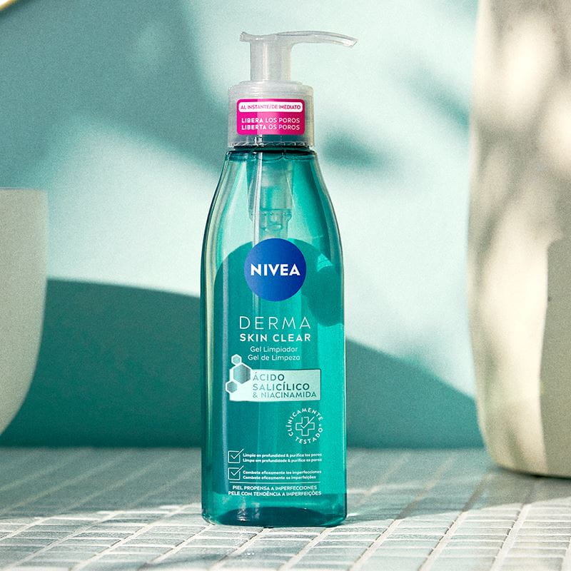 Nivea Skin Clear Gel de Limpeza pousado numa bancada de casa de banho de azulejos junto a um lavatório.