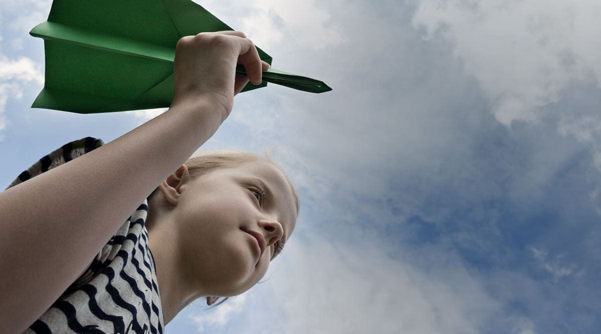 Criança com avião de papel na mão