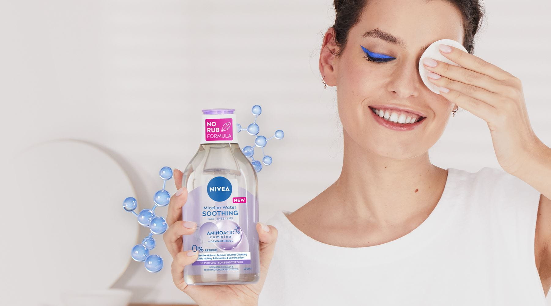 A woman has removed heavy blue eye make-up with the NEW NIVEA Micellar Water and shows the cotton pad.