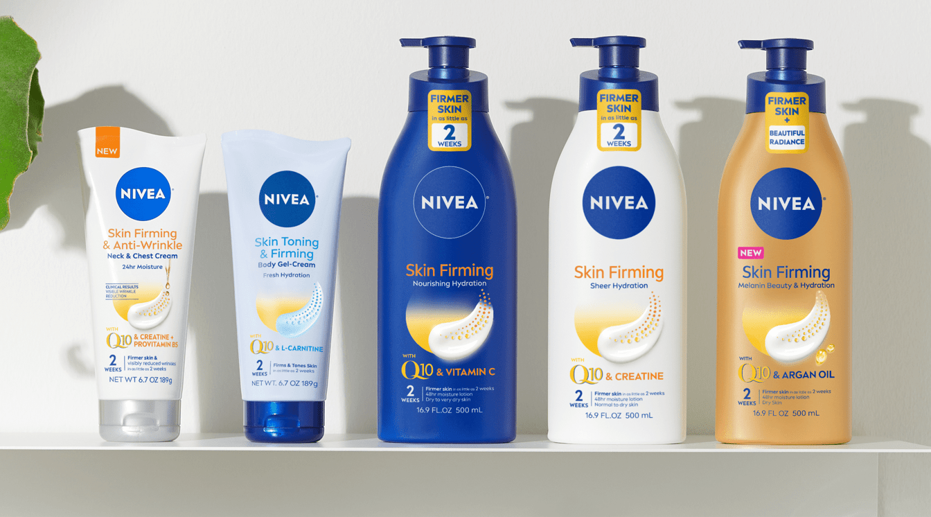 5 Nivea products are lined up on a shelf.  There is a plant in a white ceramic vase on the furthermost left side.  Next to the plant are 5 Nivea products.  In line-up order these products are: NEW NIVEA Skin Firming & Anti-Wrinkle Neck & Chest Cream with Q10, NIVEA Skin Toning & Firming Gel-Cream with Q10 & L-Carnitine, NIVEA Skin Firming Nourishing Hydration Body Lotion with Q10 & Vitamin C, NIVEA Skin Firming Sheer Hydration Body Lotion with Q10 & Creatine and NEW NIVEA Skin Firming Melanin Beauty & Hydration Body Lotion with Q10